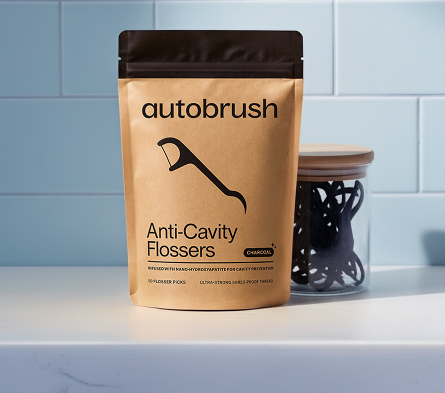 Autobrush anti-cavity flossers packaging on a bathroom shelf with a light blue tiled wall. #flosserss