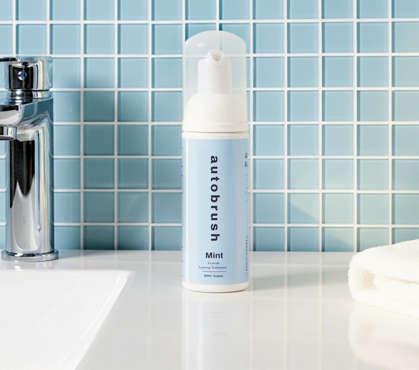 Autobrush mint toothpaste tube on a bathroom counter with a tiled wall background. #foamtoothpaste