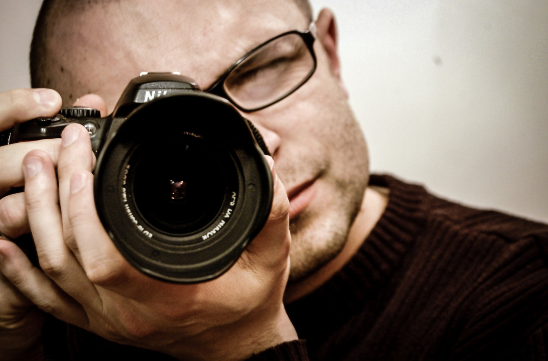 Man wearing glasses pointing a camera, for AutoBrush