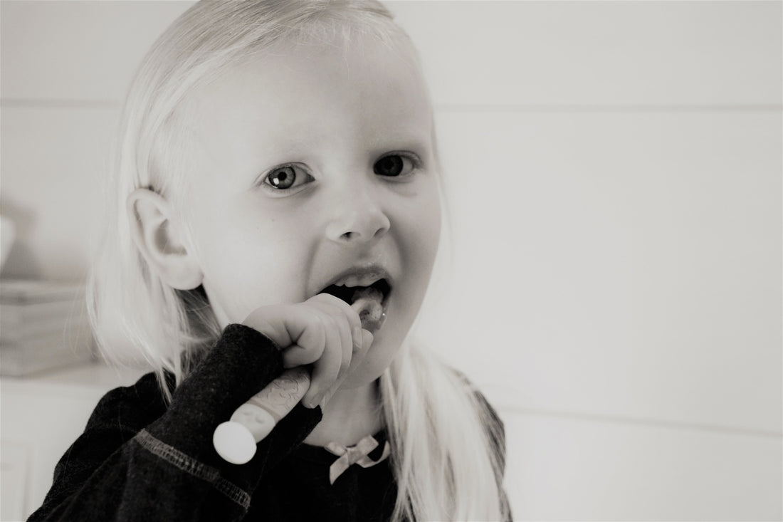 Black and white image of blonde little girl brushing her teeth, for AutoBrush