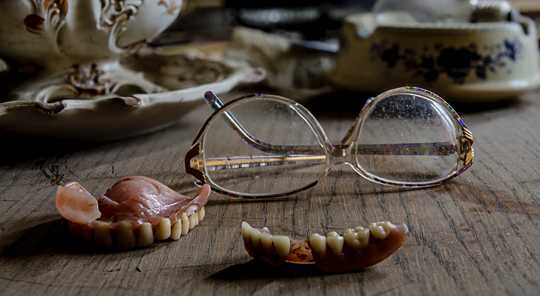 Reading glasses and a pair of dentures on top of a wooden table, for AutoBrush