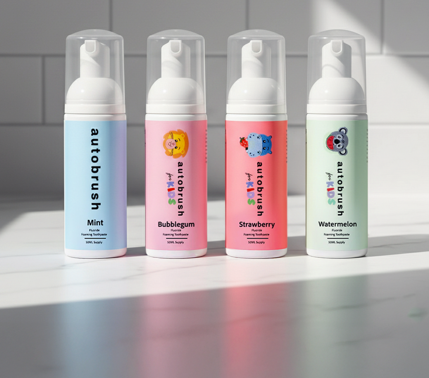 Four bottles of autobrush toothpaste on a light surface with a tiled wall background. #foamtoothpaste