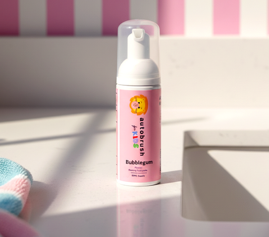 Pink bottle of bubble gum-flavored toothpaste on a white surface with a striped pink and white background. #foamtoothpaste