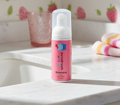 Pink bottle of Autobrush Strawberry paint on a marble surface with a strawberry-themed wallpaper in the background. #foamtoothpaste